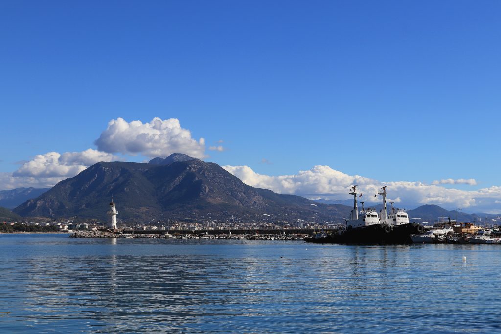 Marina bay landscape with two tows and lighthouse on breakwater pier.