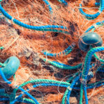 Crumpled fishnet with buoys on rope. Nautical marine background.