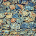 Rough stone background. Rocky masonry cobblestones cladding wall texture.
