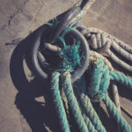 Concrete pier surface. Iron mooring rings. Lots of rope knots leading to moored boats. Nautical marine background.
