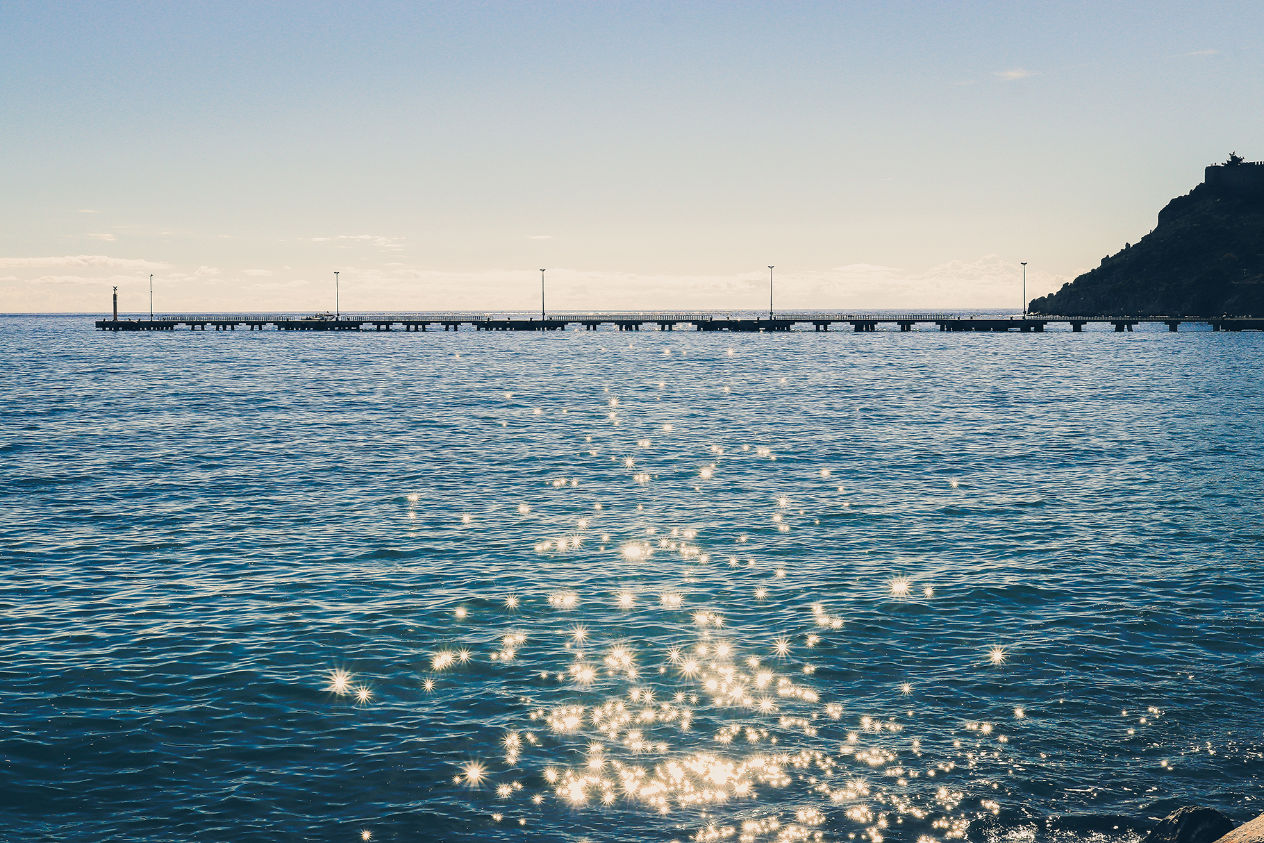 Long pier in the sea with sunshine reflection landscape.