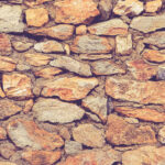 Rocky masonry cobblestones cladding wall texture. Rough stone background