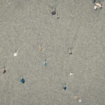 Rare pebble background. Different stones with stains on the wet sand. Beach beauty backdrop.
