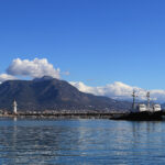 Marina bay landscape with two tows and lighthouse on breakwater pier.