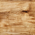 Natural oak wood surface showcasing its grain patterns and textures. The wood has a warm, light brown color with knots and variations, highlighting its organic beauty.