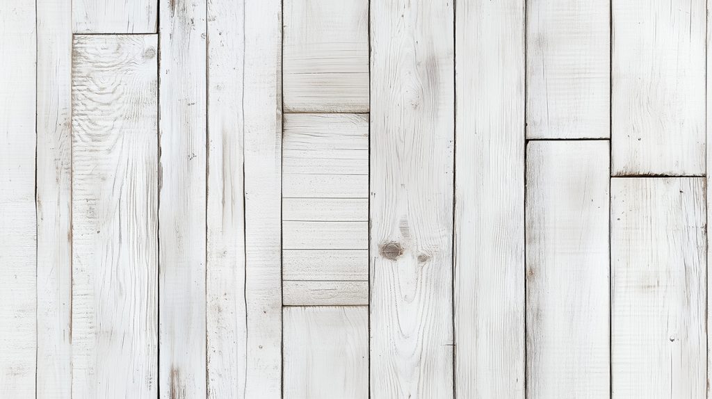 White wooden planks arranged in a rustic pattern. The wood has a weathered appearance with varying textures and shades of white, creating a clean and bright aesthetic.